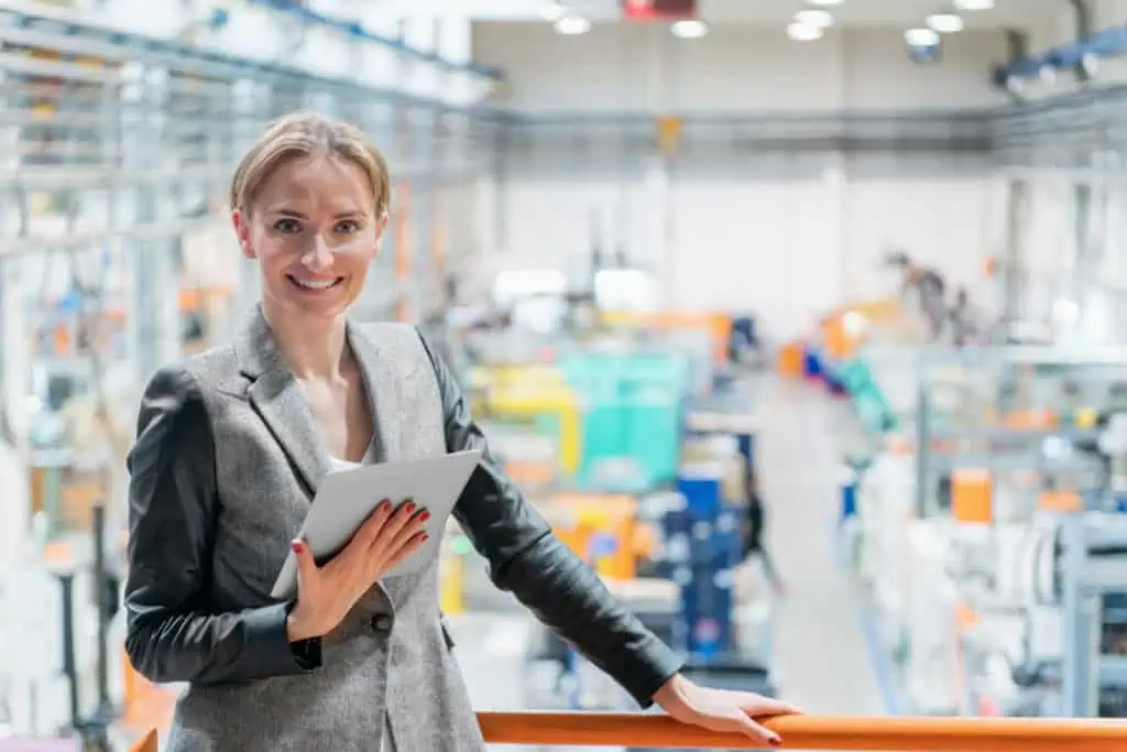 Erfolgreiche Planerin steht vor ihrem Ergebnis der fertig geplanten Fabrik im Hintergrund