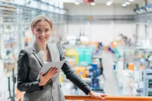 Successful production planner stands in front of her result of the finished planned factory in the background