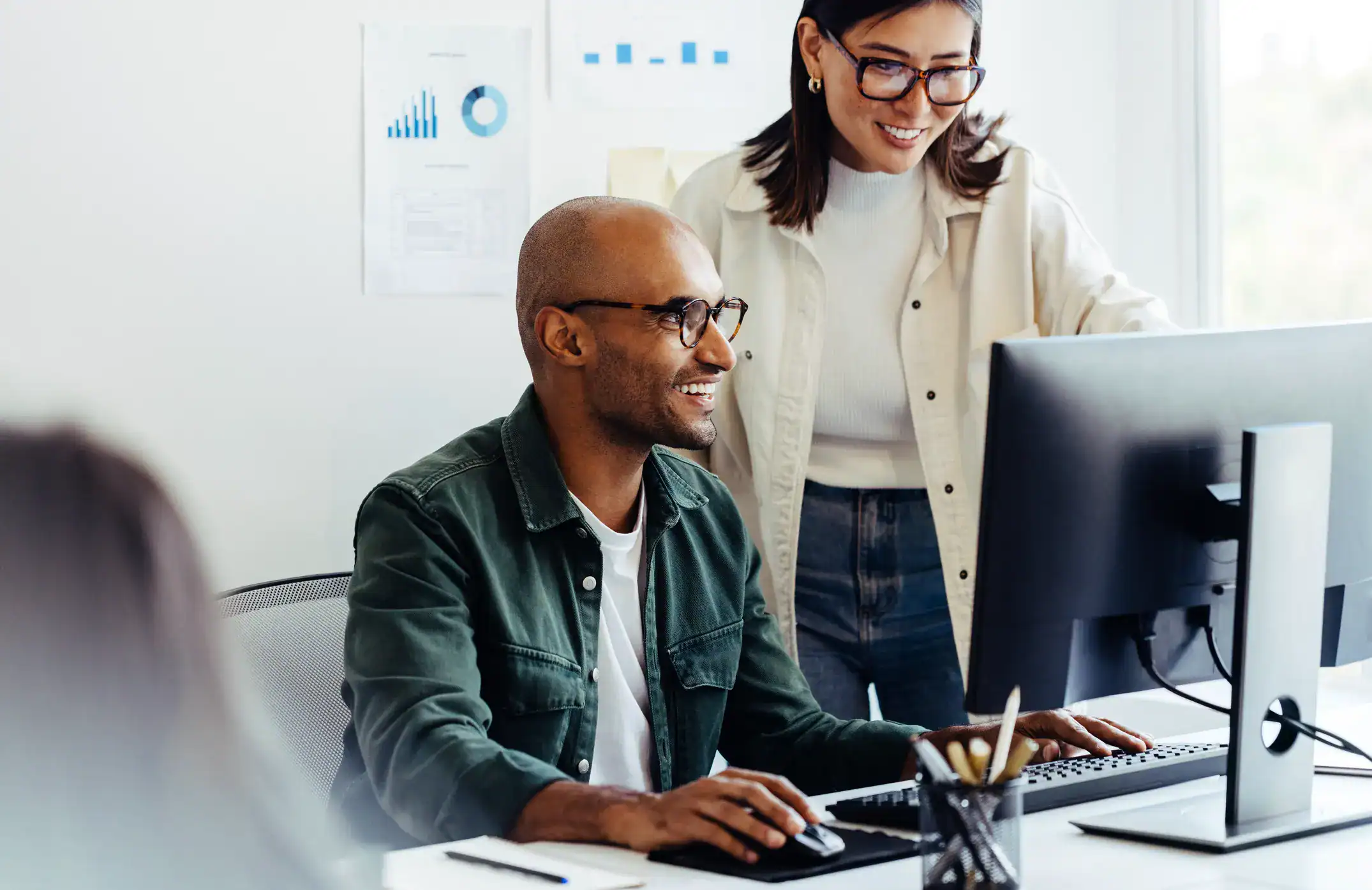 a woman and a man standing in front of a monitor smiling